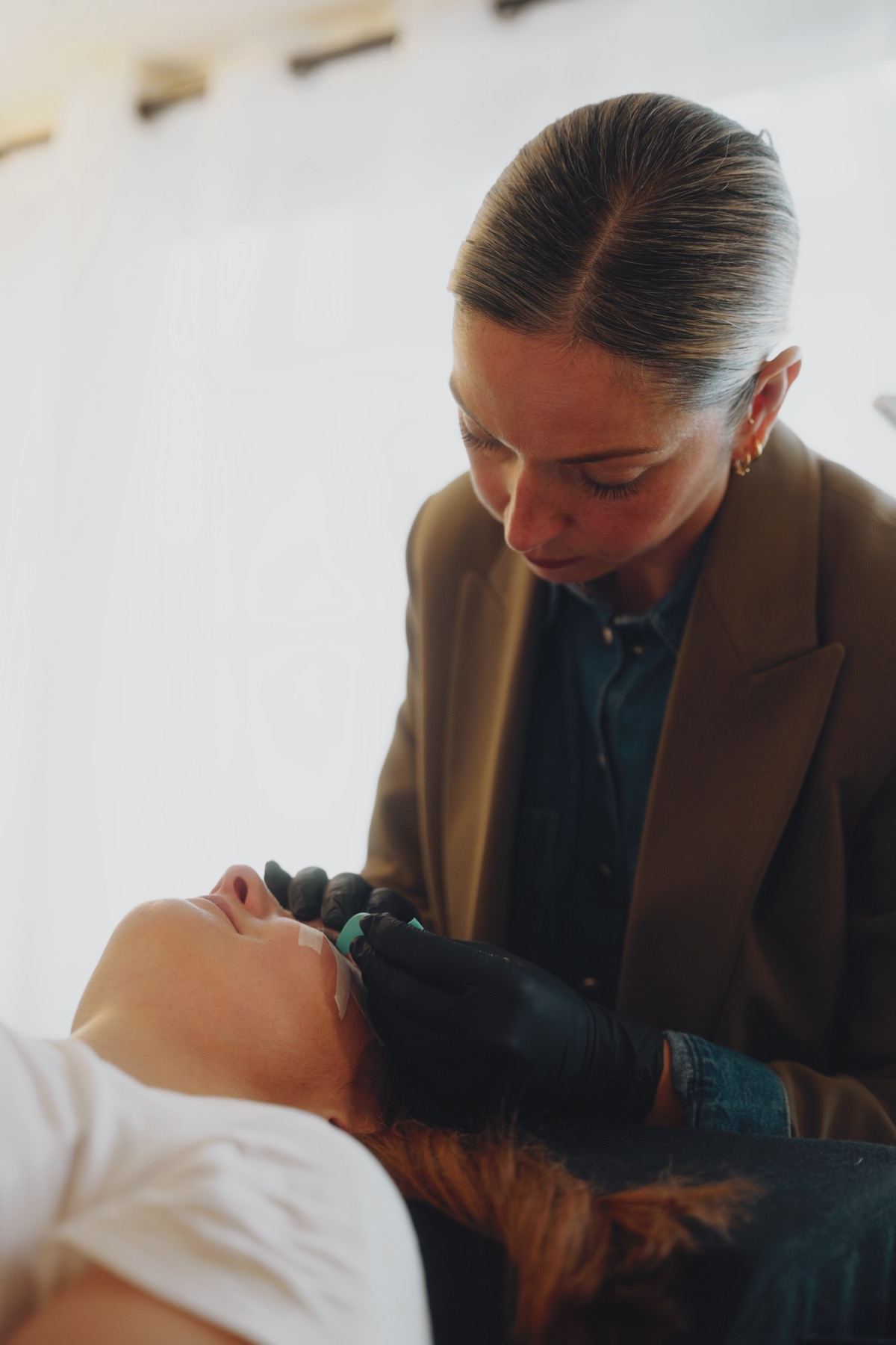 Claire Degli-Esposti au travail sur l'œil d'une cliente allongée, dans son espace d'Aix-les-Bains