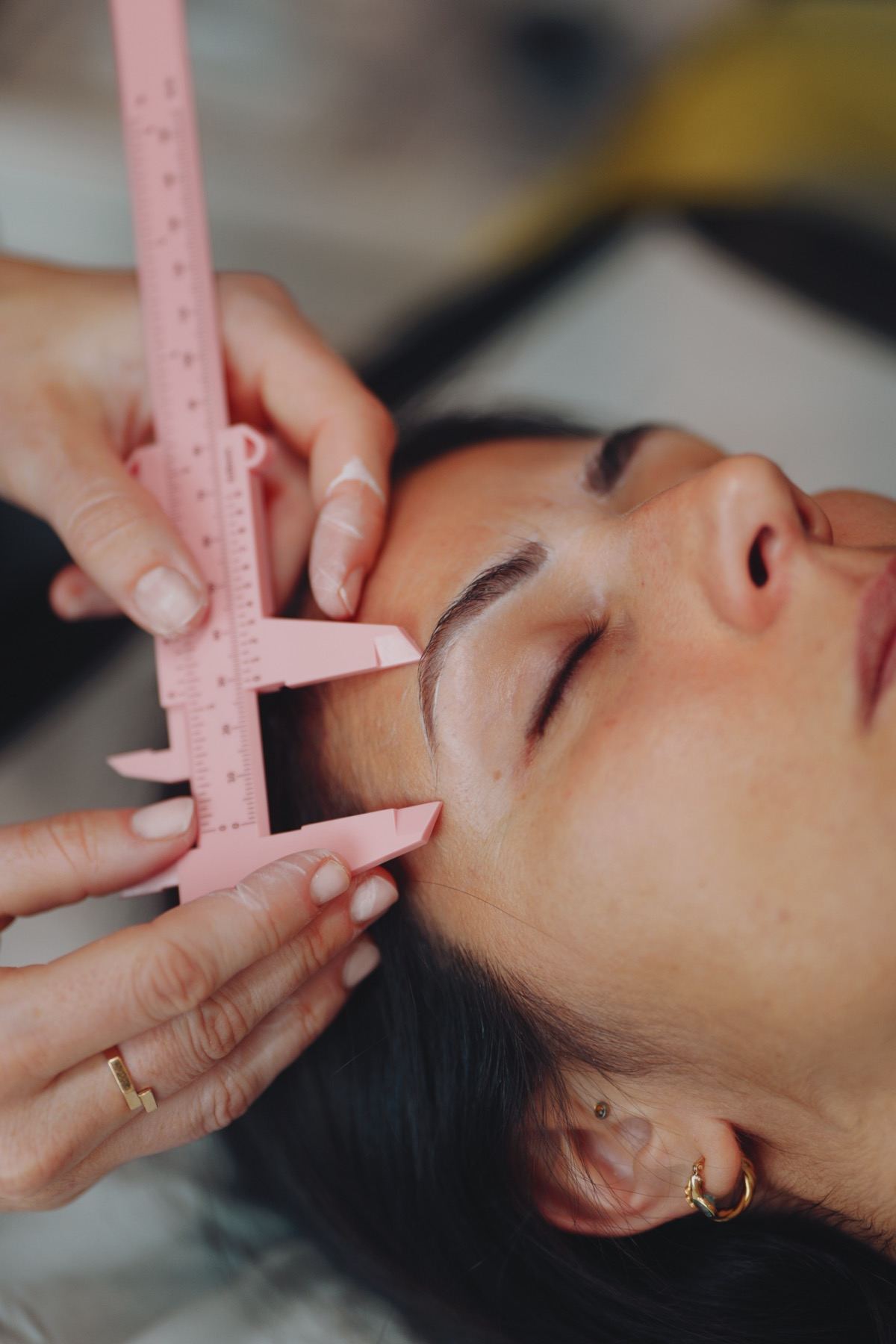 Compas de mesure rose posé sur le sourcil d'une cliente pendant la préparation d'un maquillage permanent, Claire Degli-Esposti Aix-les-Bains
